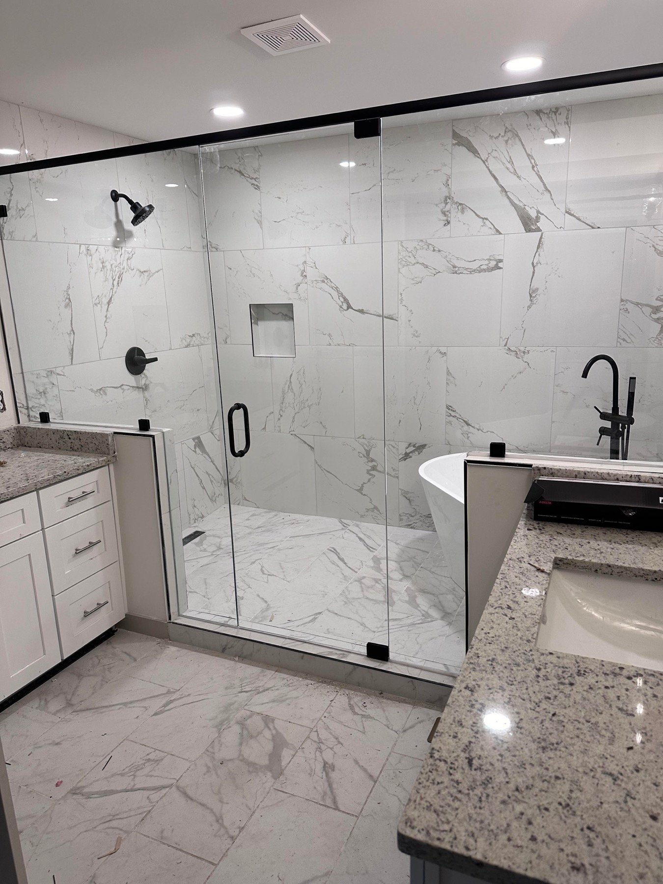Glass shower with marble-effect tile walls and black fixtures