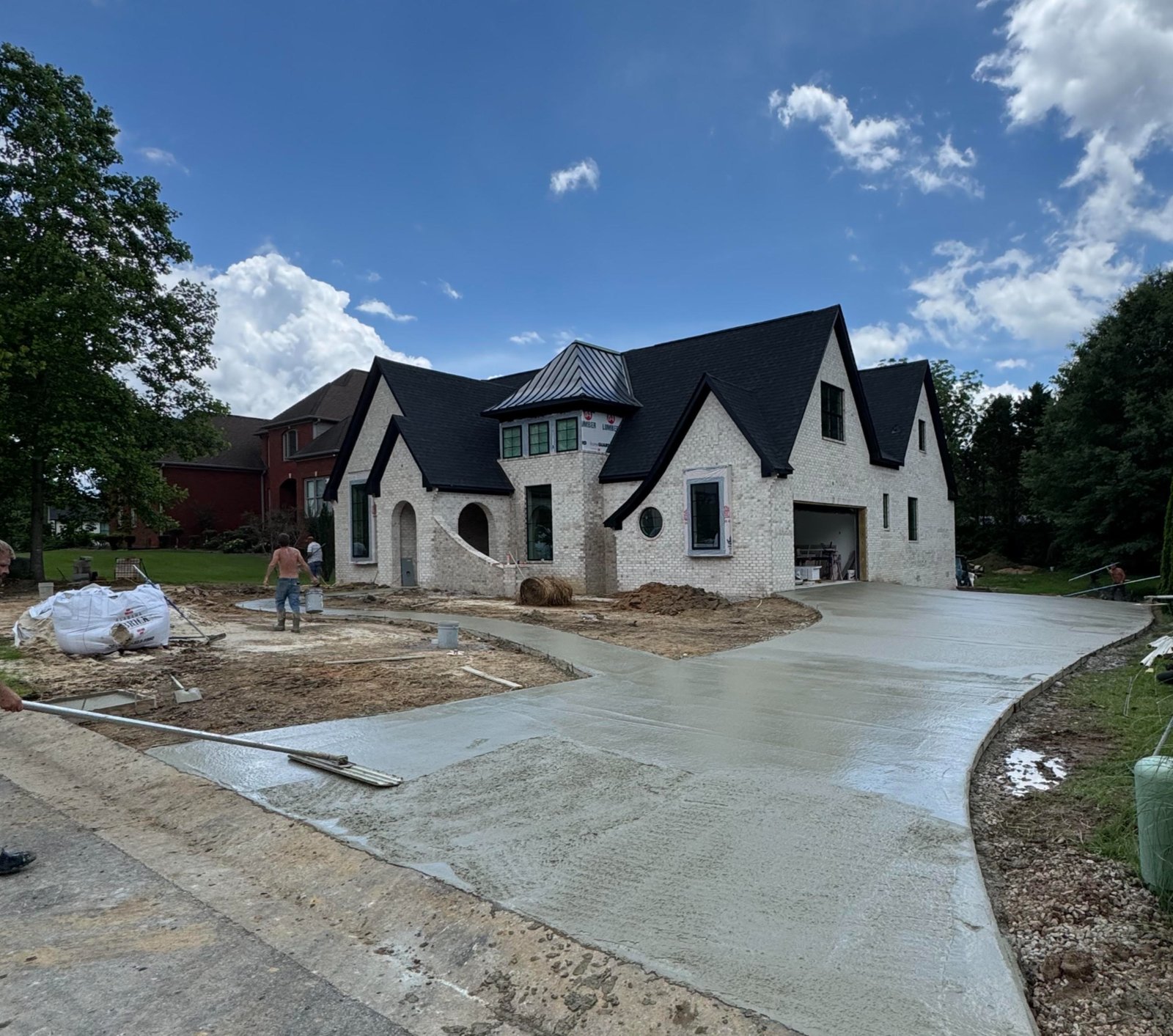 White brick custom home with a black roof under construction