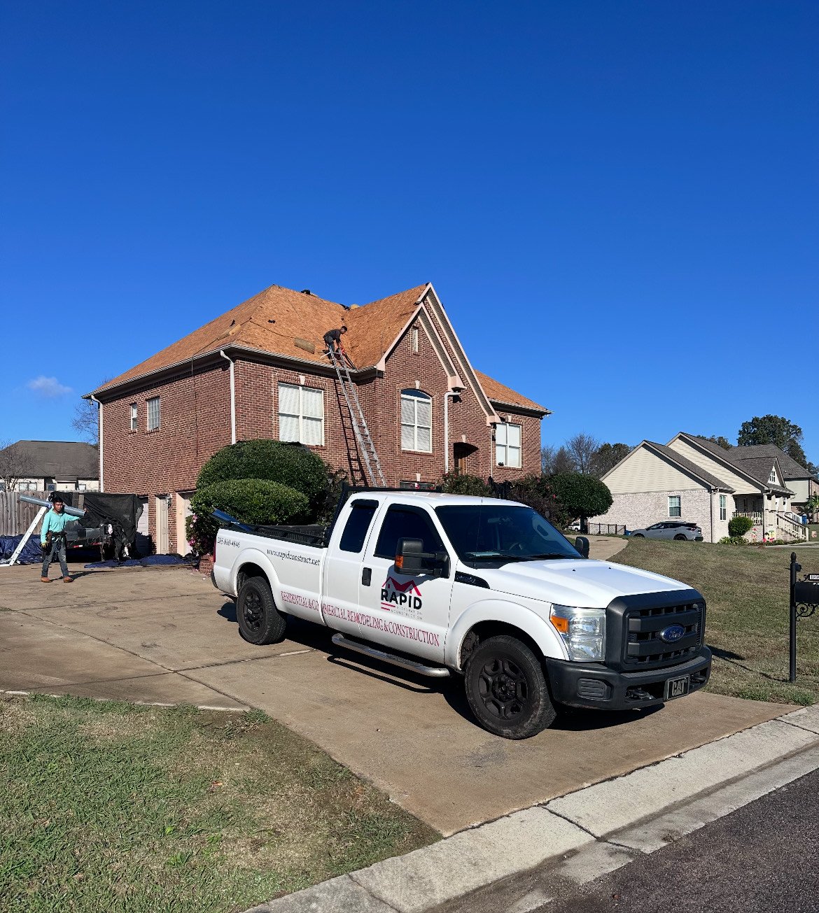 Rapid branded truck outside a brick home with residential roofing work in progress